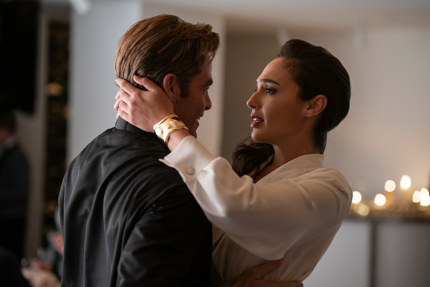Gal Gadot embracing Chris Pine with her face close to his and her hand on back of his head, looking into his eyes.