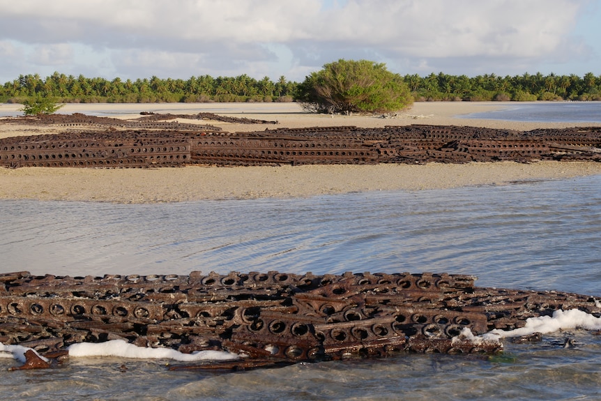 Piles of rusting perforated steel planking near the water. 