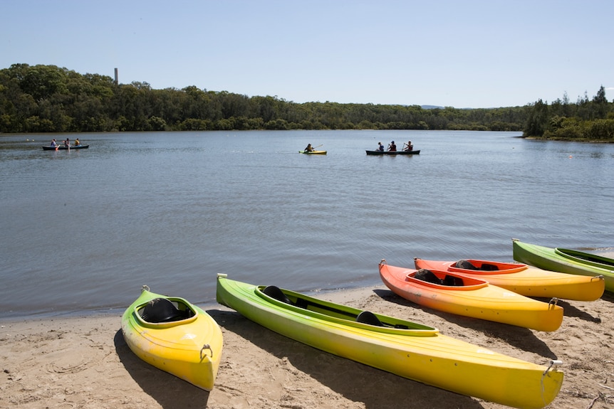 Three empty kayaks on the shore of a lake