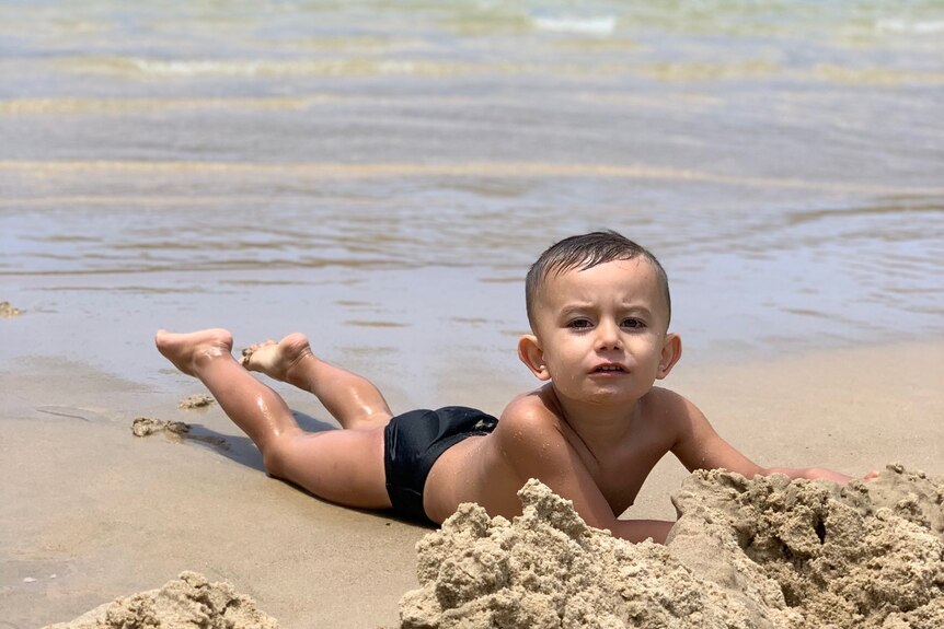 Trey laying on the sand at the beach