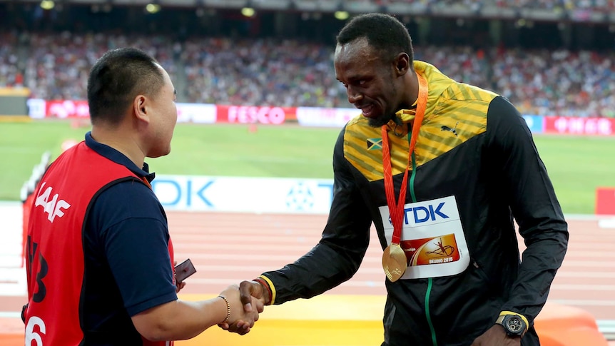 Usain Bolt of Jamaica shakes hands with Tao Song of CCTV