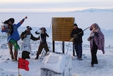 Five people in pirate costumes smile at a research base in Antarctica.