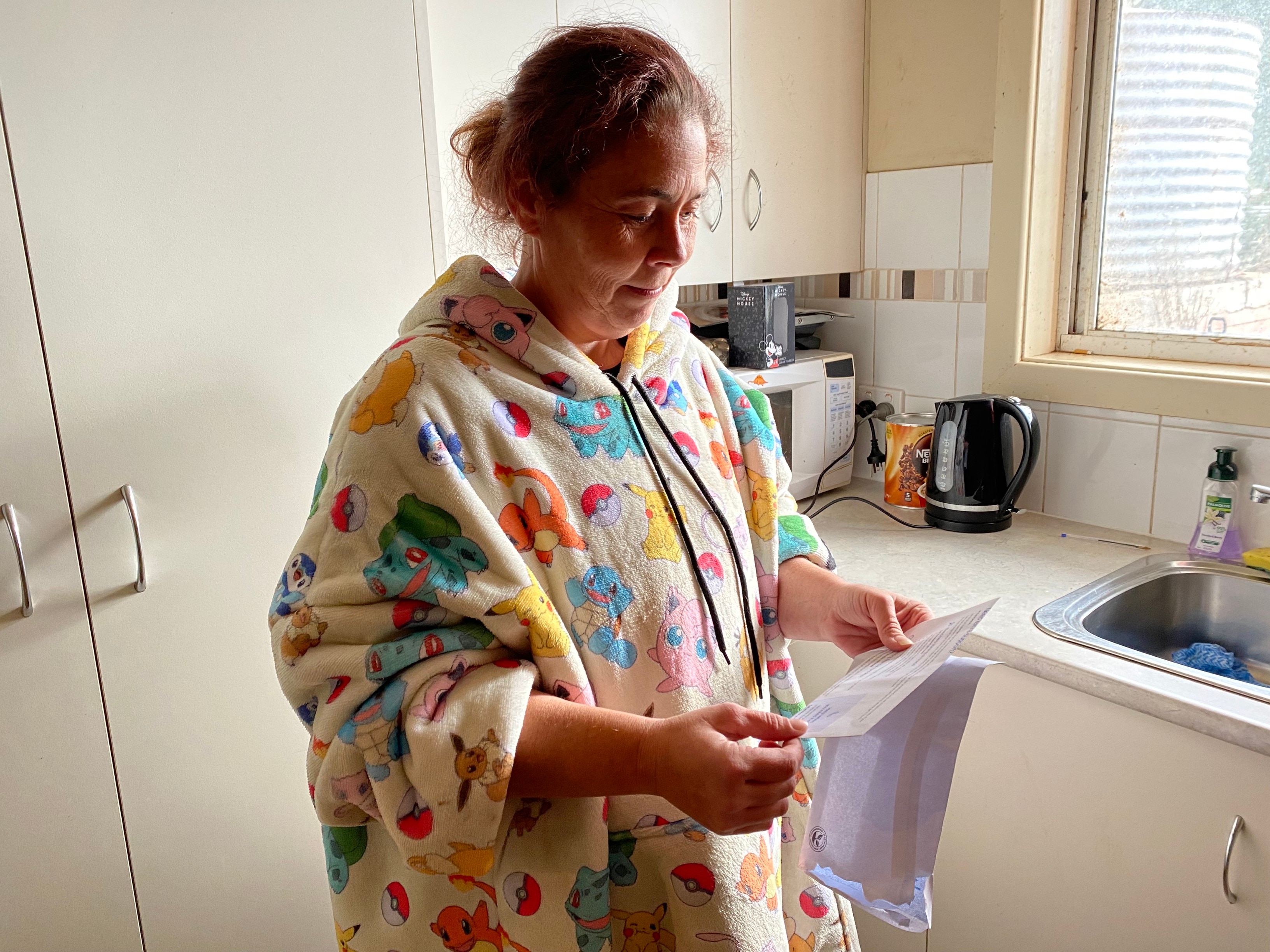 A woman wearing a pokemon hoodie looking down at an envelope in her hands
