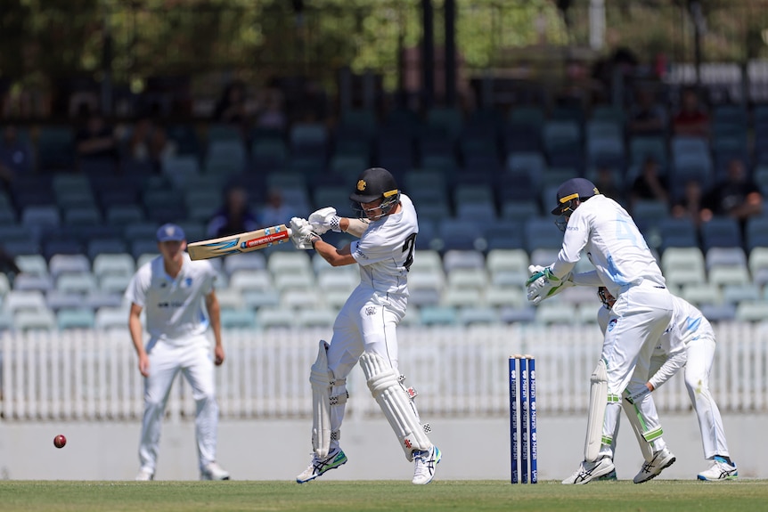 A left-handed batsman leans back and drives a shot on the off-side while fielders and the wicket-keeper watch.