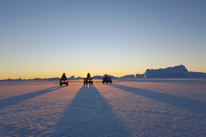 Final golden light shines over Antarctica. The coloured buildings of Davis station can be seen in the background.