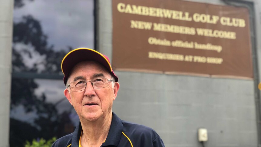 Man in a brown cap in front of a sign for Camberwell Golf Club