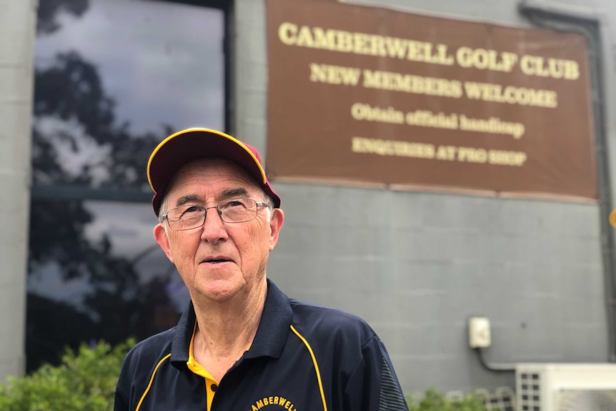 Man in a brown cap in front of a sign for Camberwell Golf Club