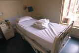 A hospital bed with white sheets in a hospital room
