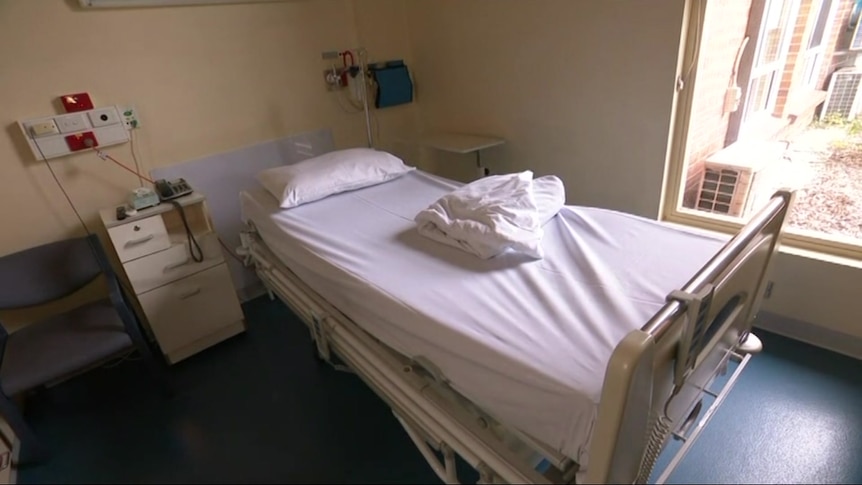 A hospital bed with white sheets in a hospital room