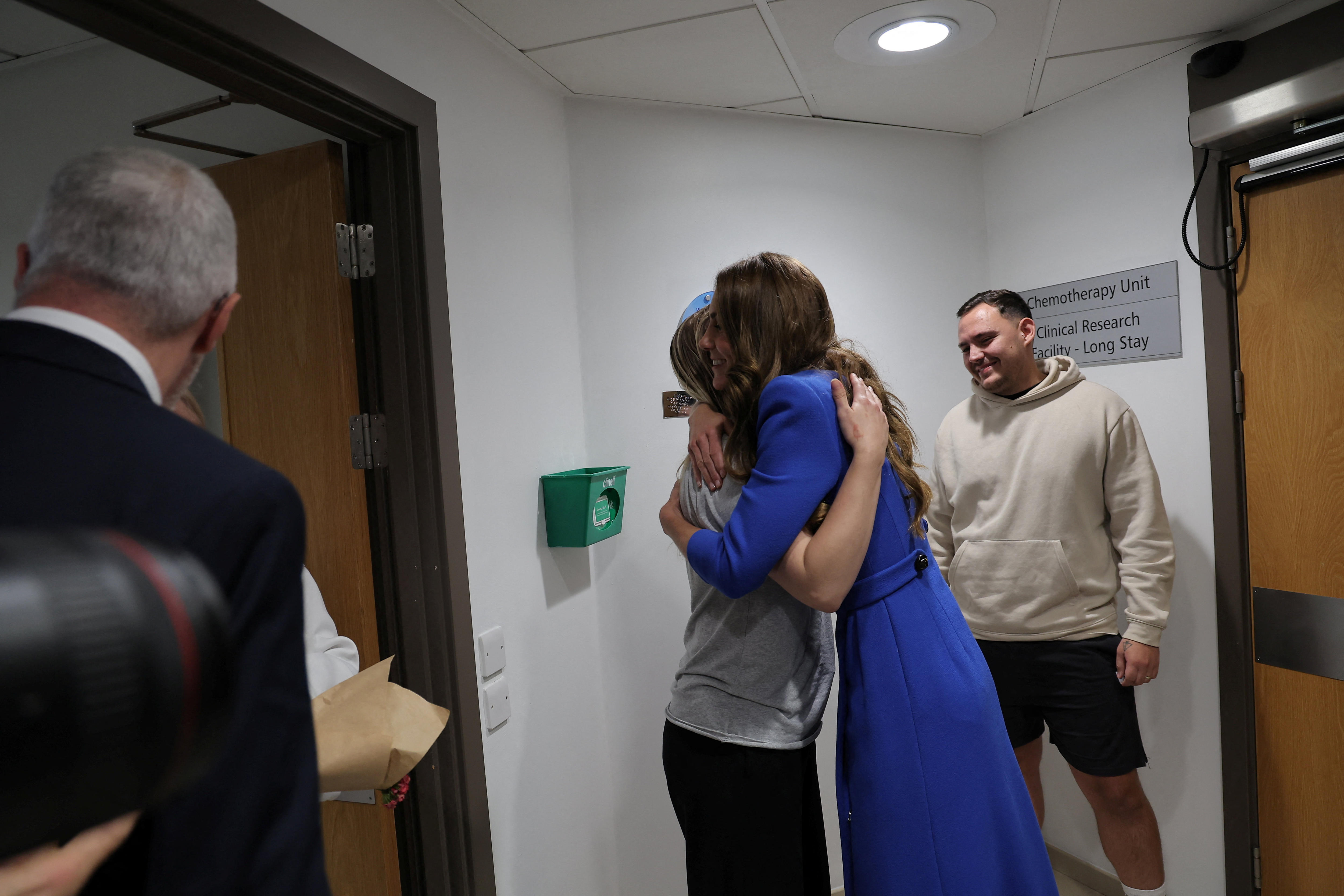 Princess Kate embracing cancer patient Claire with Claire's husband standing by watching