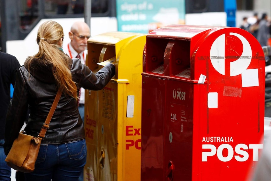 Woman posts a letter in the express Australia Post box.
