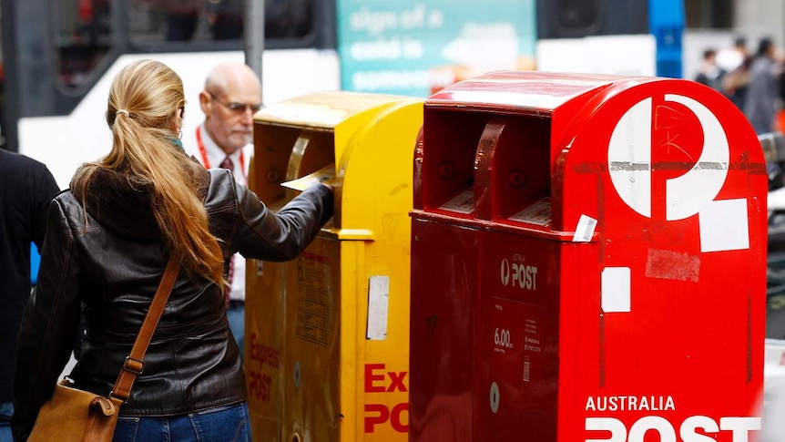 Woman posts a letter in the express Australia Post box.