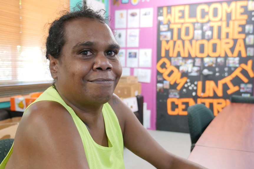 Portrait of Aboriginal woman with "Welcome to the Manoora Community Centre" sign in background