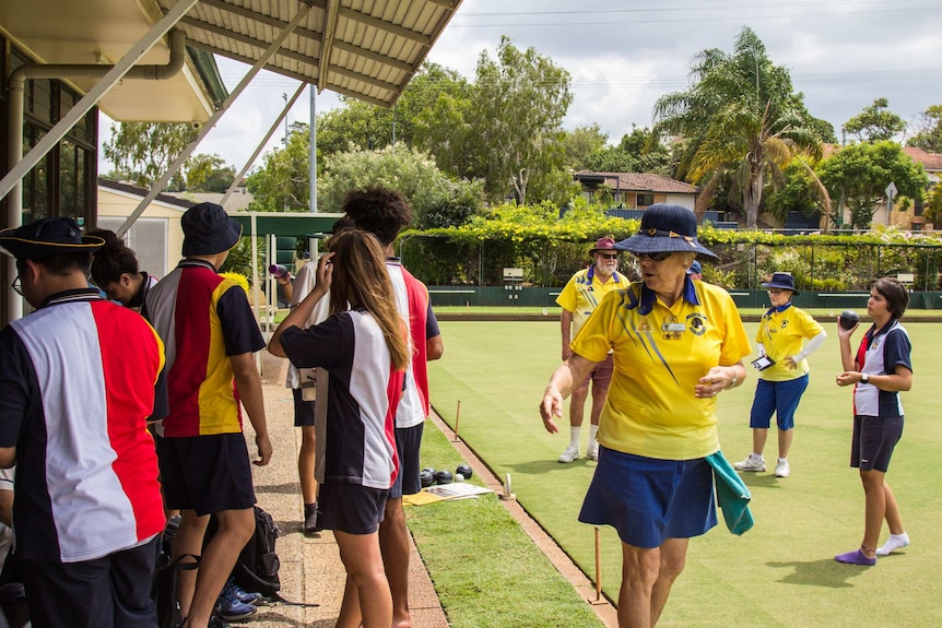 Students and older members organise themselves on the lawn bowls green.