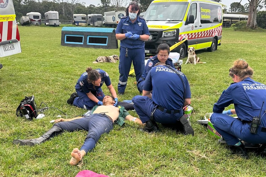 A man on the ground is treated by paramedics.
