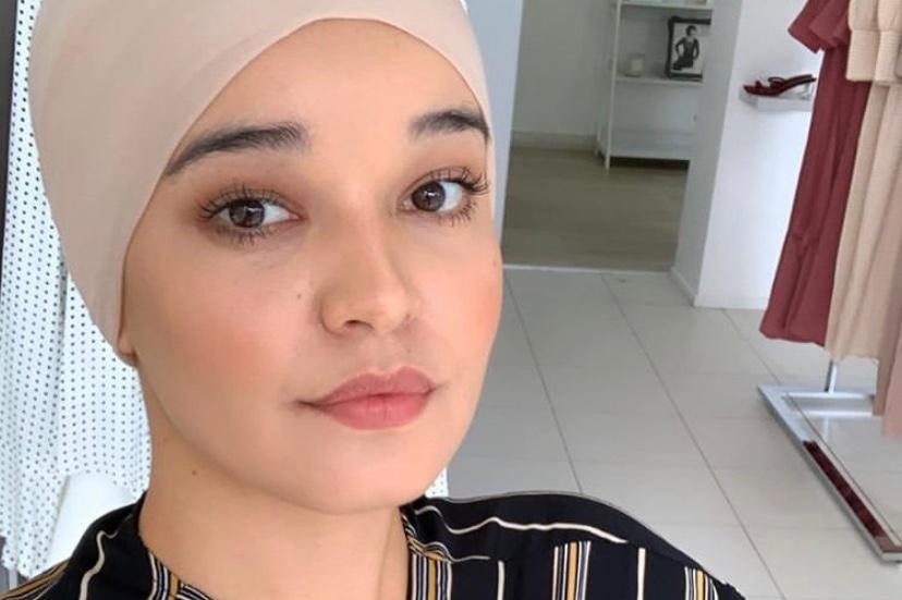 A woman with a pink hijab in a clothing store.