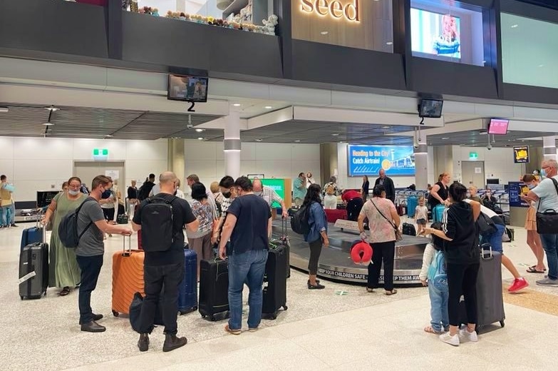 People with suitcases at the airport baggage collection.