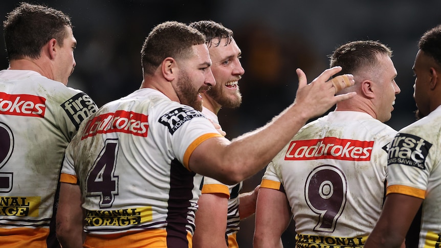 A group a rugby league players celebrate a win