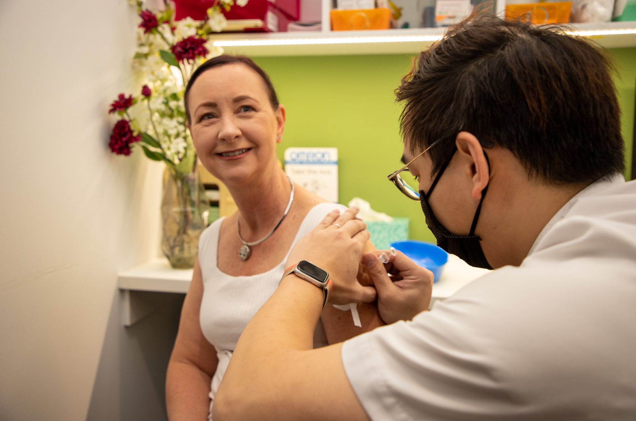Yvette D'Ath in a white singlet smiling as she gets a needle.