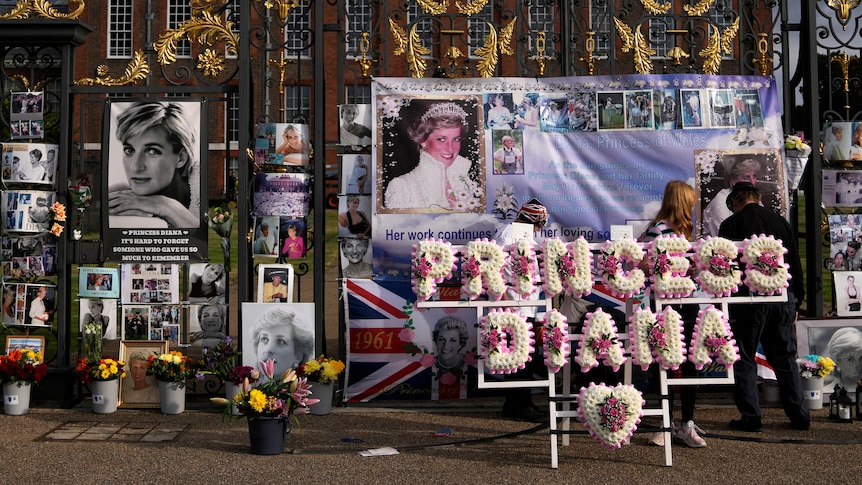 A floral arrangement spelling out Princess Diana stands in front of photos of her. 