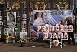 A floral arrangement spelling out Princess Diana stands in front of photos of her. 