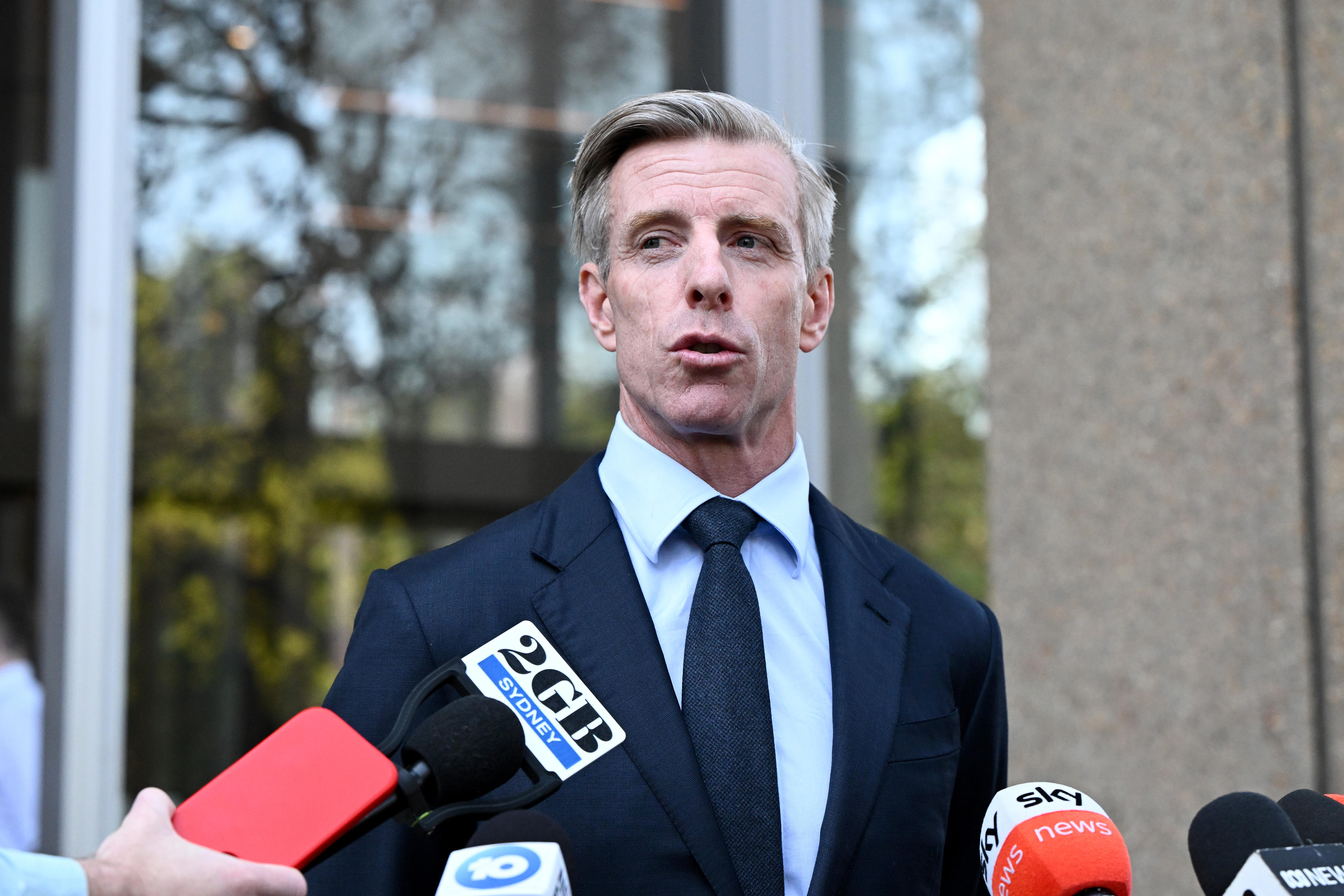 Justin habla vestido de traje, con micrófonos frente a él.