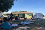 Four residents, a dog, two tents and a green house are pictured