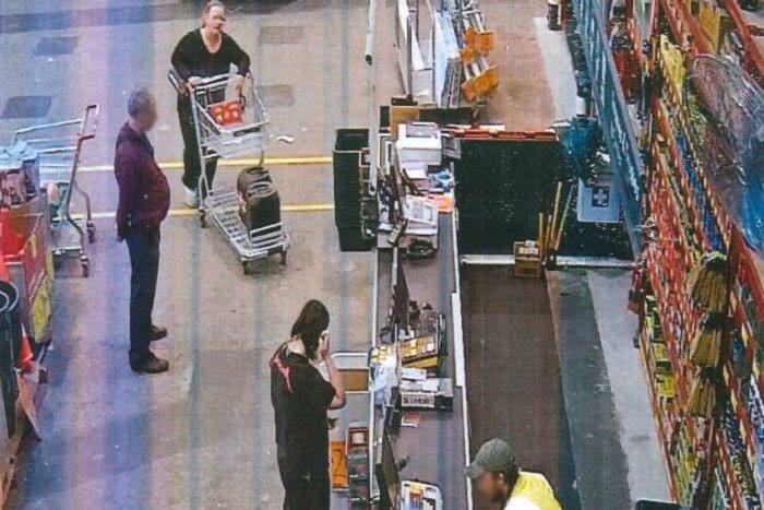 Jemma Lilley and Trudi Lenon stand at a hardware store counter with a trolley holding containers of hydrochloric acid.