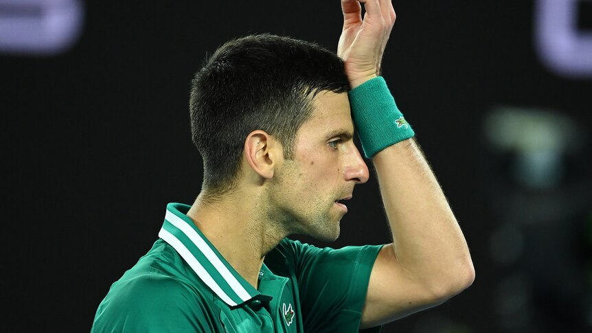 Novak Djokovic holds his hand to his forehead on court at the Australian Open in 2021.