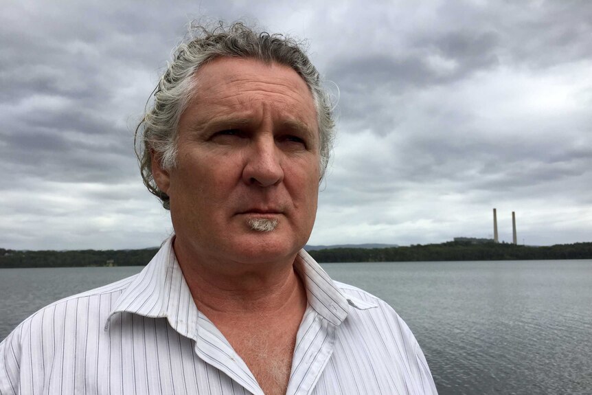 A headshot of a man looking out with Lake Macquarie in the background.