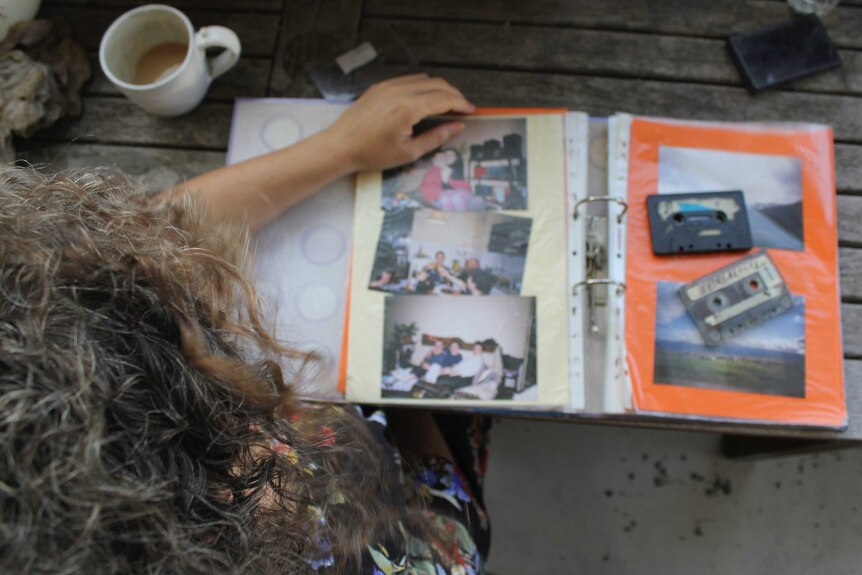Overhead shot of a woman with long hair looking through an out-of-focus photo album.