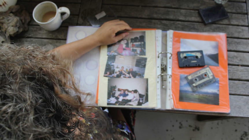 Overhead shot of a woman with long hair looking through an out-of-focus photo album.