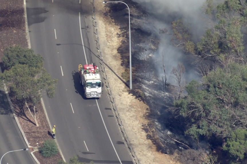 Un camión de bomberos en una carretera cerca de tierra quemada. 