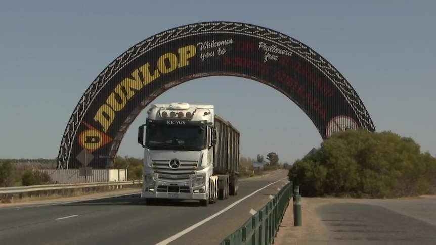 A giant half tyre over a truck on a highway