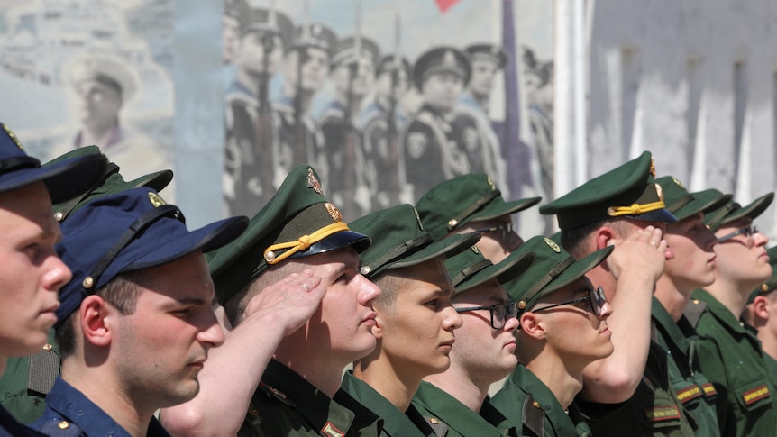 Russian conscripts standing in a line saluting. 