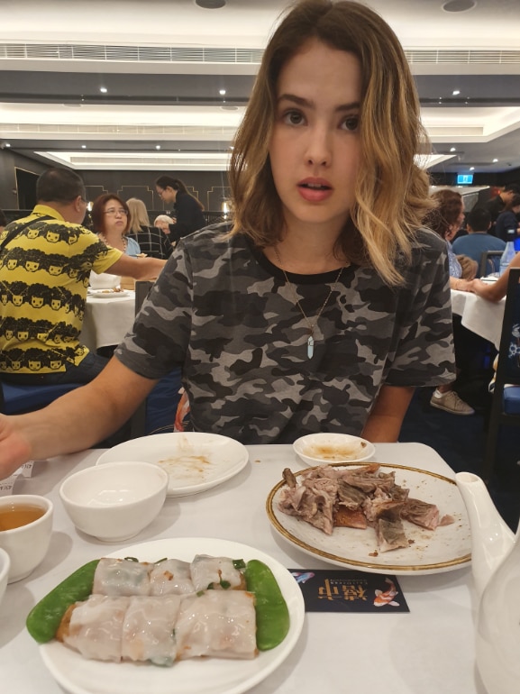 A young woman at a restaurant in an article written by her mother, Yumi Stynes.