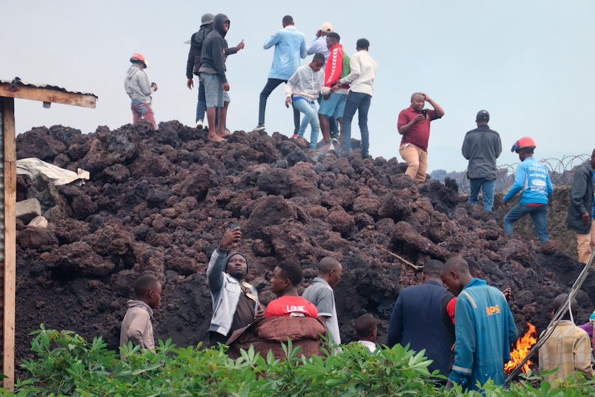 People take photos and look at mountain of lava rocks.