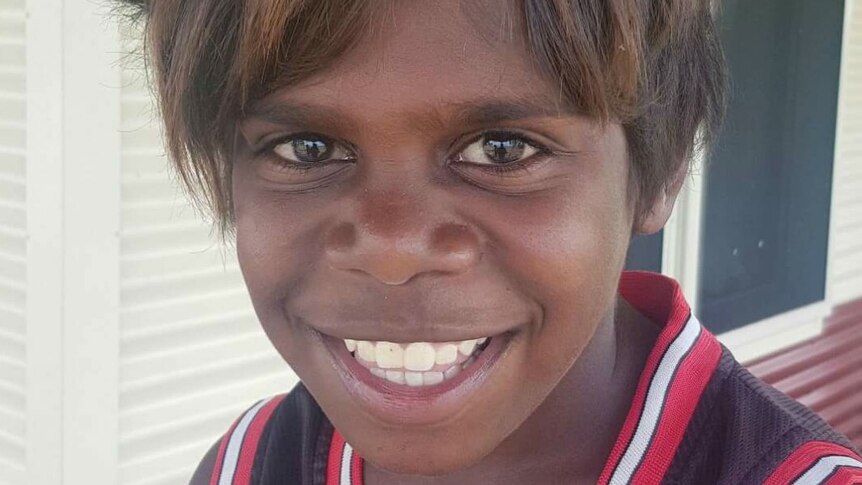 A close-up of a young, smiling Indigenous boy wearing a sleeveless top.