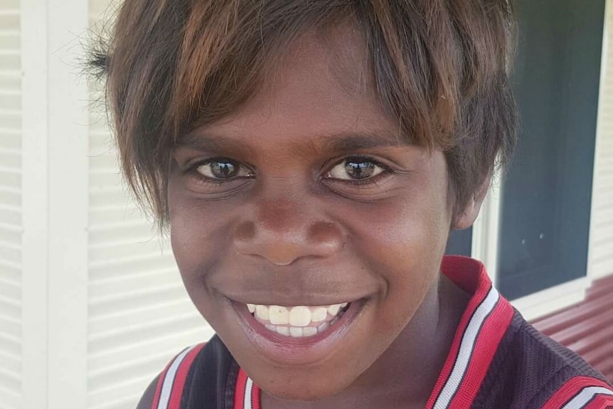 A close-up of a young, smiling Indigenous boy wearing a sleeveless top.