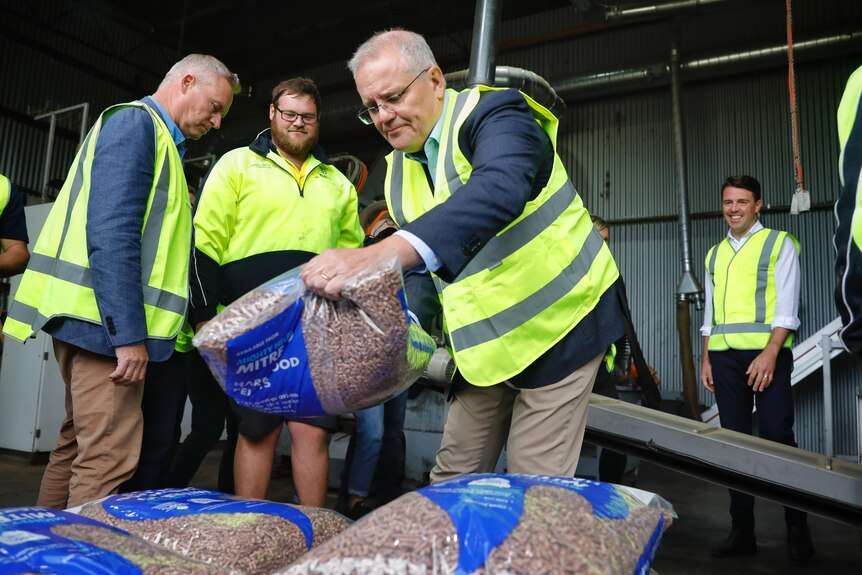 Scott Morrison carries a sack of pellets while wearing yellow high-vis.