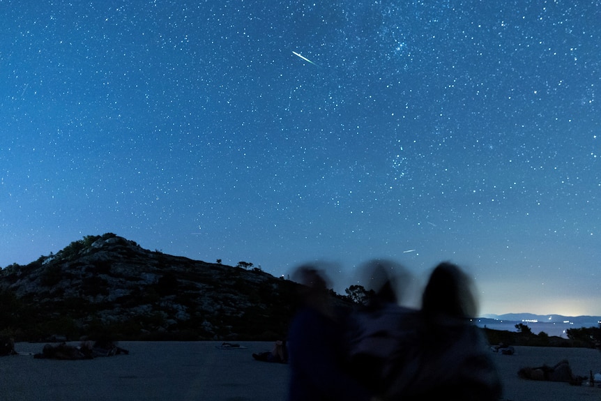 A meteor with a long white tail in the night sky