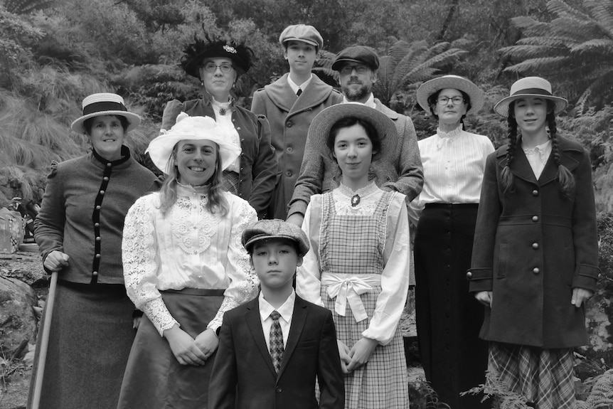 A group of women, a man and some children, dressed in Edwardian clothes, in a natural spot.