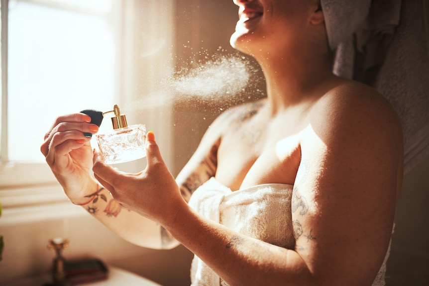 Cropped shot of a young woman spraying perfume during her morning beauty routine.