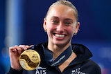 Alysha Koloi shows of her gold medal at the 2024 World Aquatics Championships.