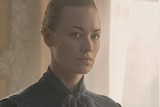 A still image from The Handmaid's Tale shows Yvonne Strahovski's character with a stern expression on her face.