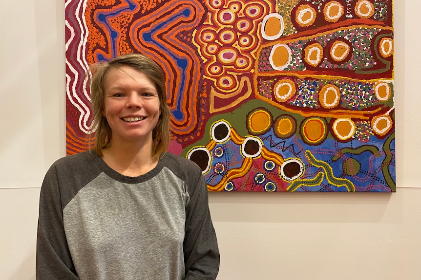 a woman smiles in front of patterned artwork