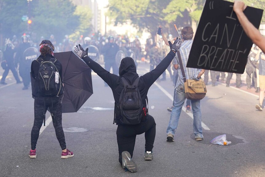 Demonstrators kneel in front of a line of police officers during a protest for the death of George Floyd