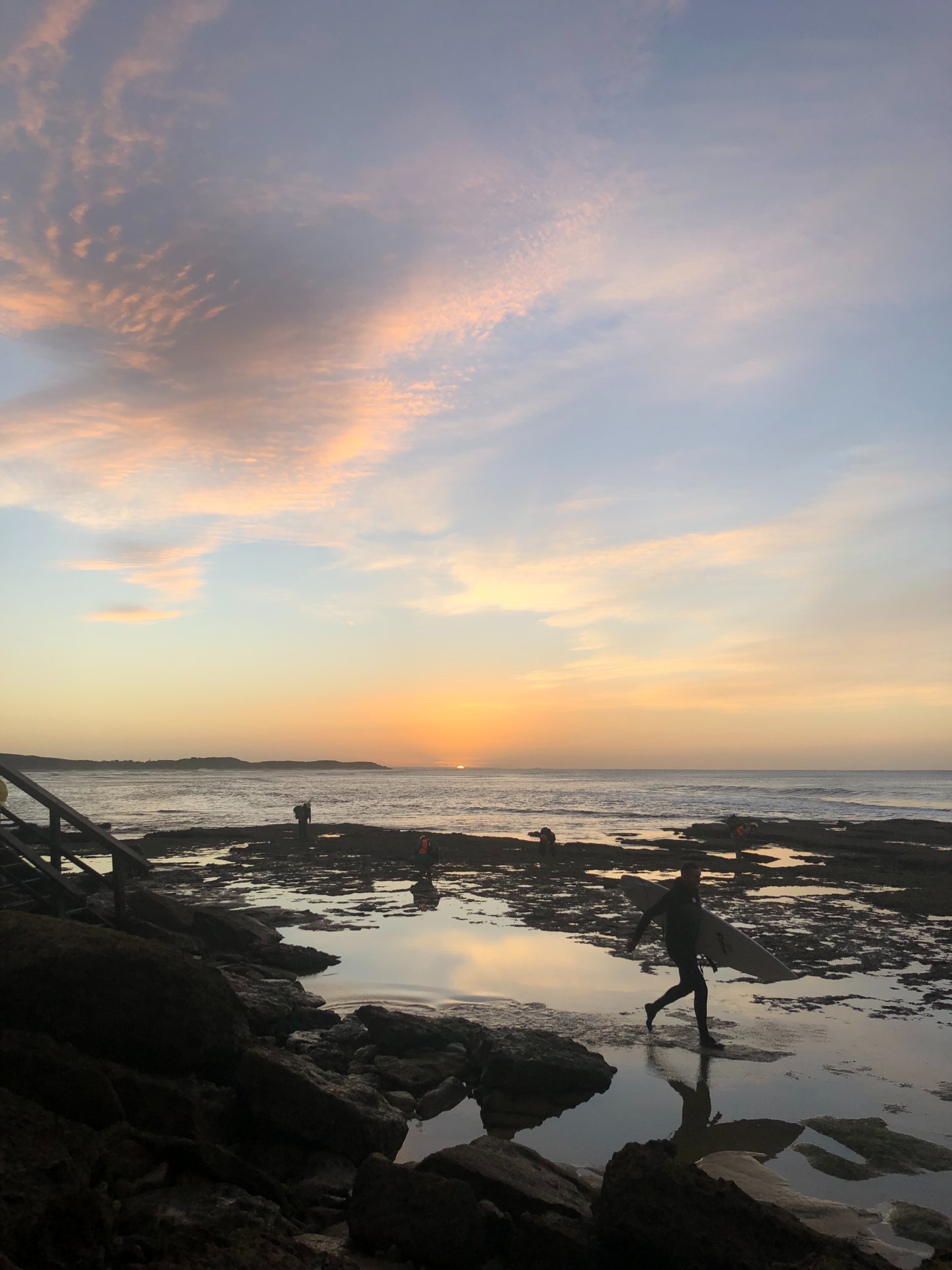 A sunrise over the ocean with a surfer silhouetted in the foreground