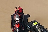 A man puts his arm around a boy on a South Stradbroke Island beach shortly after a person died reportedly falling off a jet ski.