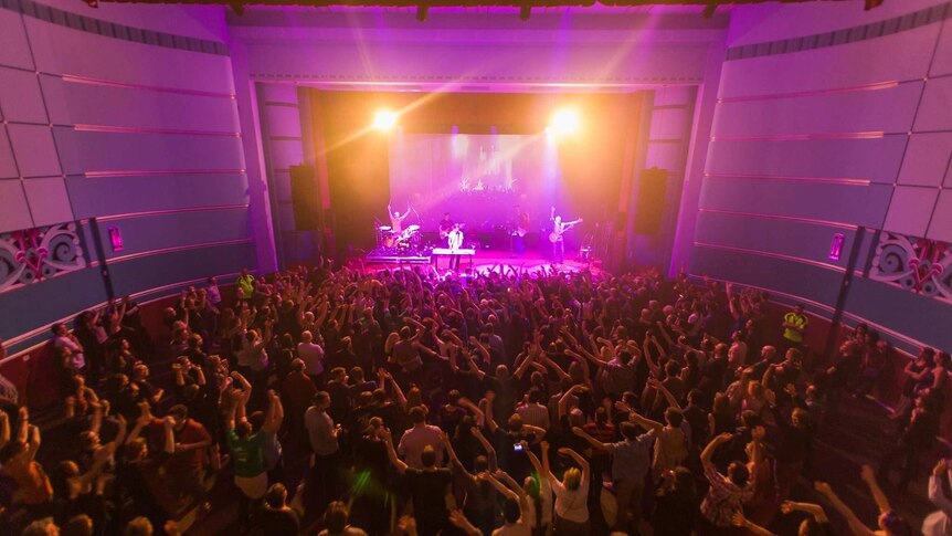 A sea of people enjoy a rock concert at an indoor venue